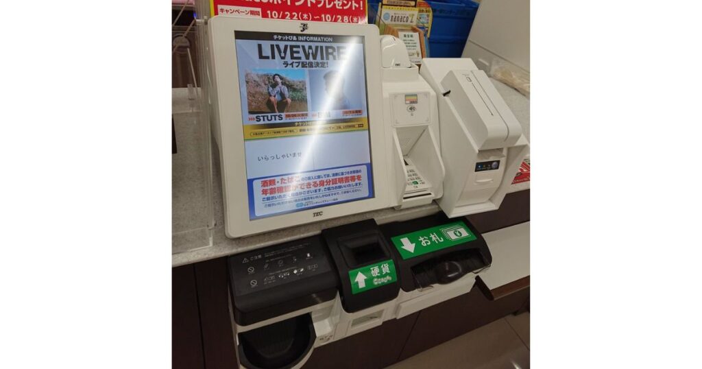 セブン-イレブンのセルフレジ端末の写真。画面には「LIVEWIRE」のチケット情報と「20歳以上ですか?」という年齢確認の日本語メッセージが表示されている。