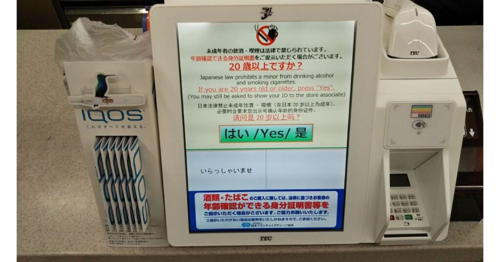 コンビニのカウンターにあるセルフレジ端末の写真。画面には「20歳以上ですか?」という年齢確認の日本語メッセージと、大きな「はい」ボタンが表示されている。