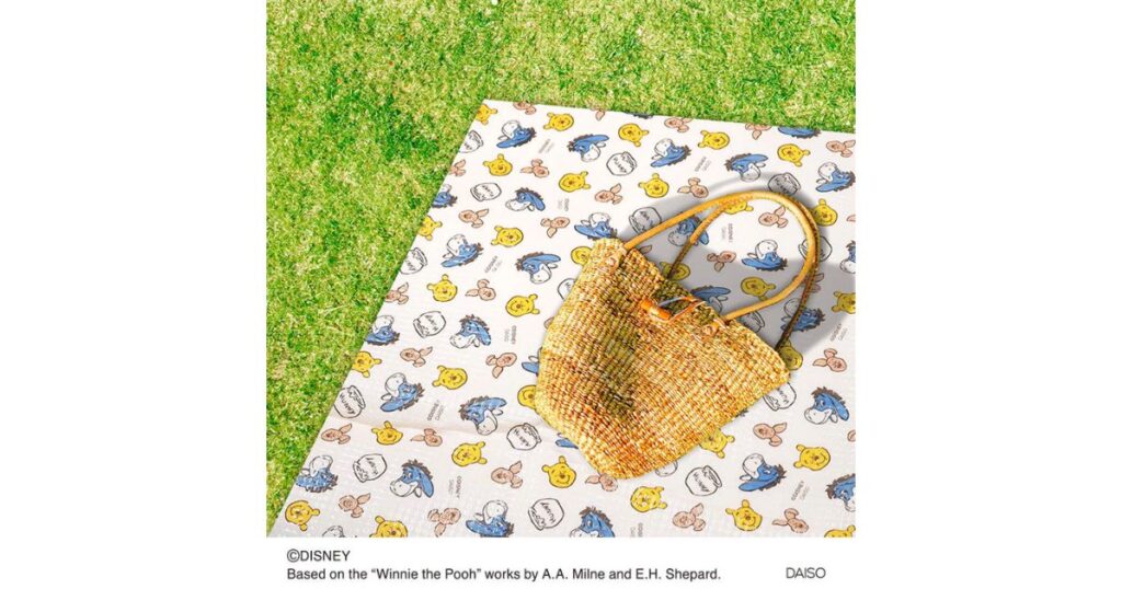 芝生の上に広げられたダイソーの「くまのプーさん」柄のレジャーシートとカゴバッグ