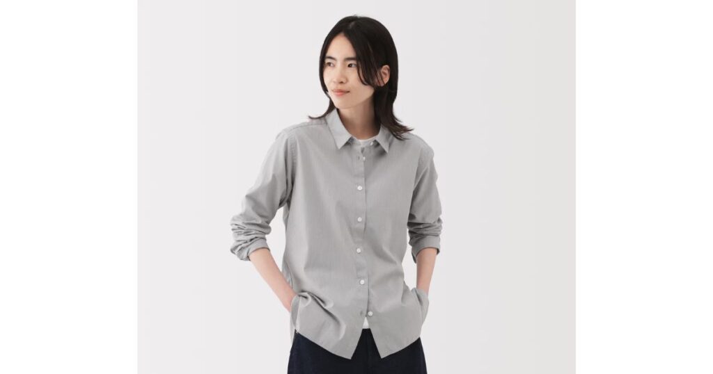 グレーの長袖シャツを着用し、両手をポケットに入れた男性の全身カット。