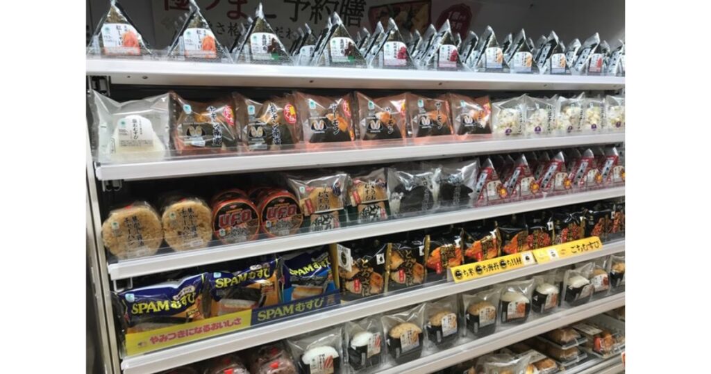 コンビニエンスストアの陳列棚に並べられた、種類豊富なおにぎりやSPAMむすびなどの商品