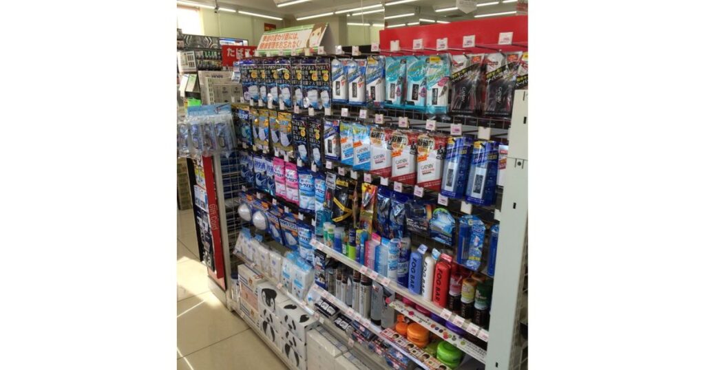 マスクやワックス、ヘアスプレーなどの日用品・トラベル用品が陳列されているコンビニの棚