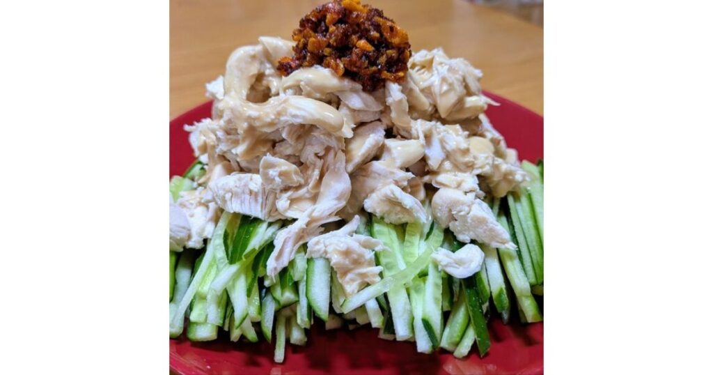 千切りきゅうりの上にほぐしたサラダチキンと食べるラー油を乗せた、バンバンジー風アレンジレシピの盛り付け画像