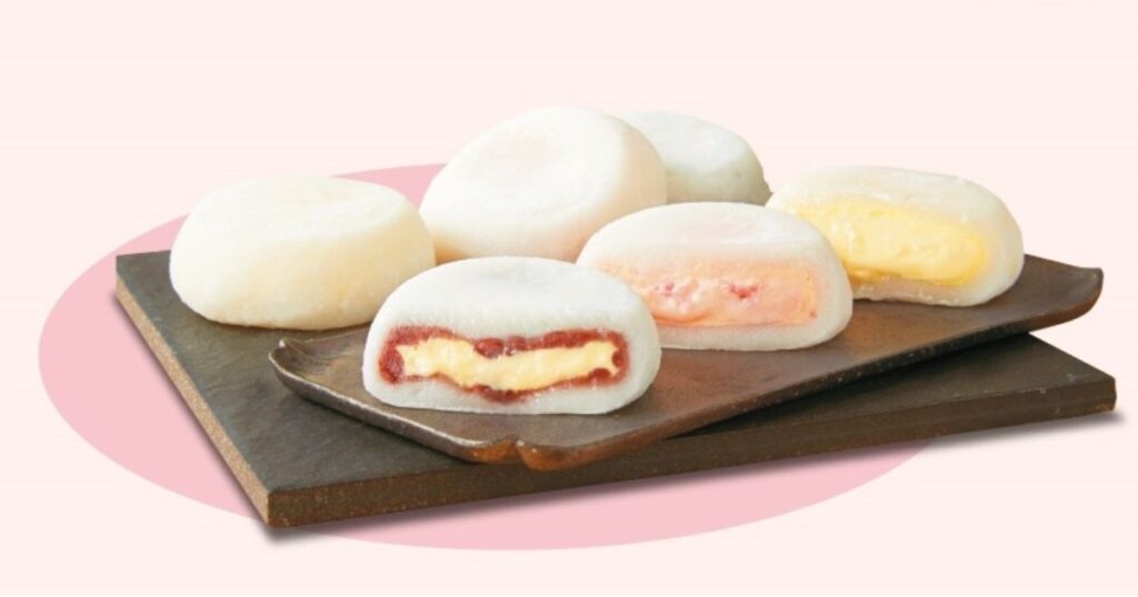 半分にカットされ、いちごソースやカスタードクリームがたっぷり詰まった色鮮やかな断面が見える生クリーム大福