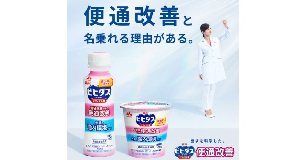 森永乳業『ビヒダス ヨーグルト 便通改善』の広告画像。機能性表示食品のボトルとカップ、白衣の女性が描かれた爽やかな背景