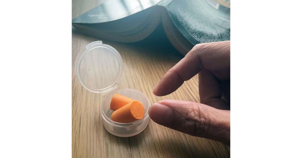 机の上に置かれた本と、透明な専用ケースに入ったオレンジ色のスポンジタイプの耳栓