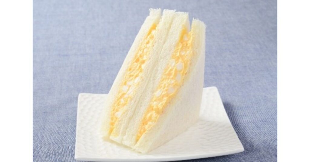 白いお皿に盛り付けられた、卵フィリングがたっぷり詰まったコンビニの卵サンド