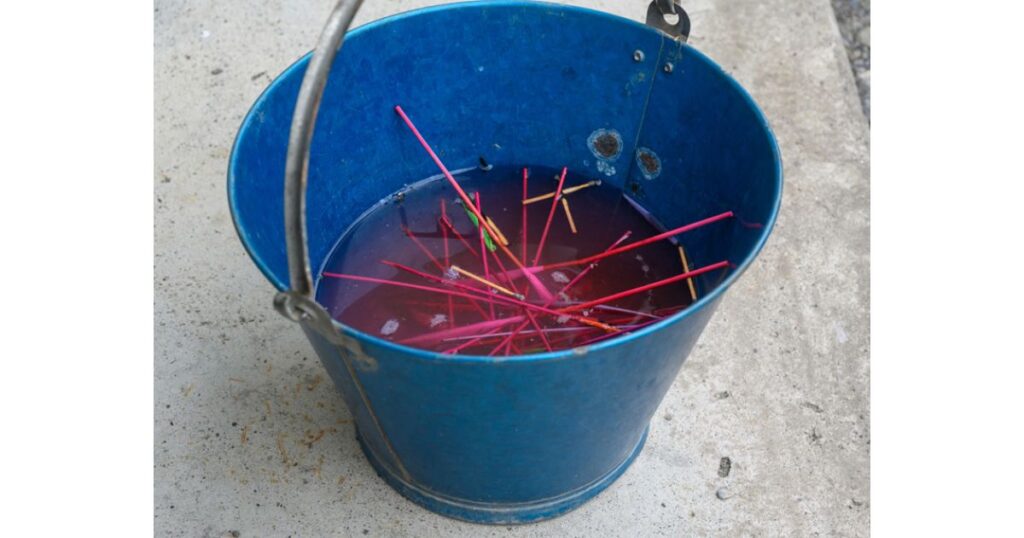 捨てる前に青いバケツの水にしっかりと浸して完全消火されている使用済みの手持ち花火