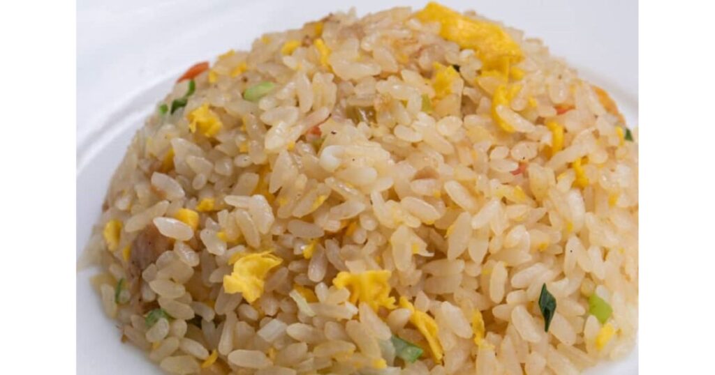 白いお皿にふんわりと盛られた、卵やネギなどの具材が入ったパラパラとした食感のチャーハン