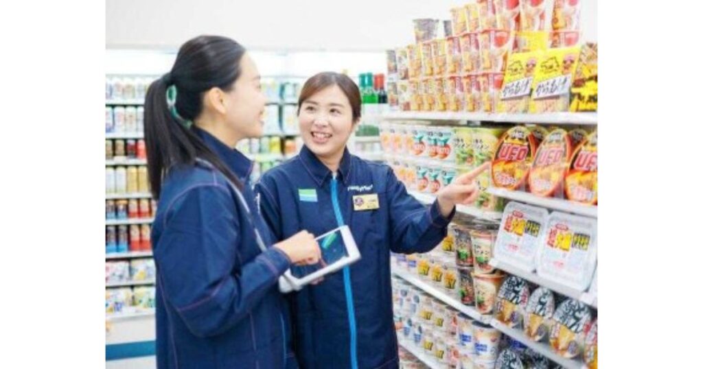 コンビニの制服を着て笑顔で業務を確認し合う2人の女性店員
