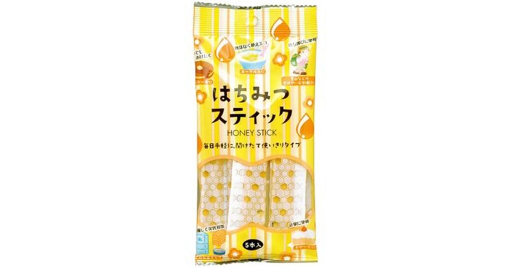 はちみつ色のパッケージに入った、ハニー・スティック（5本入り）。パッケージには、ホットケーキやヨーグルトにかけるイラストと、「毎日手軽に、開けたて使いきりタイプ」というテキストが書かれている。
