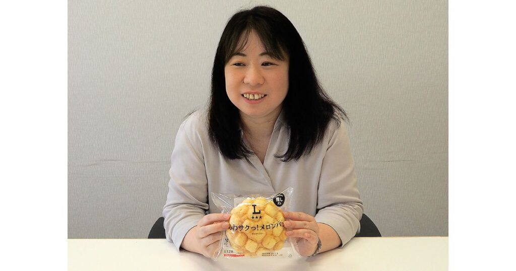 ローソンの「ふわサクっ！メロンパン」のパッケージを両手で持ち、笑顔を見せる女性の写真