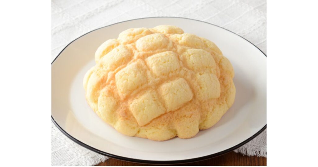 白いお皿の上に乗せられた、ふっくらとした丸いコンビニメロンパン