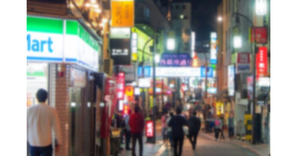 夜の繁華街に立ち並ぶ店舗やコンビニエンスストアの光るネオンサイン