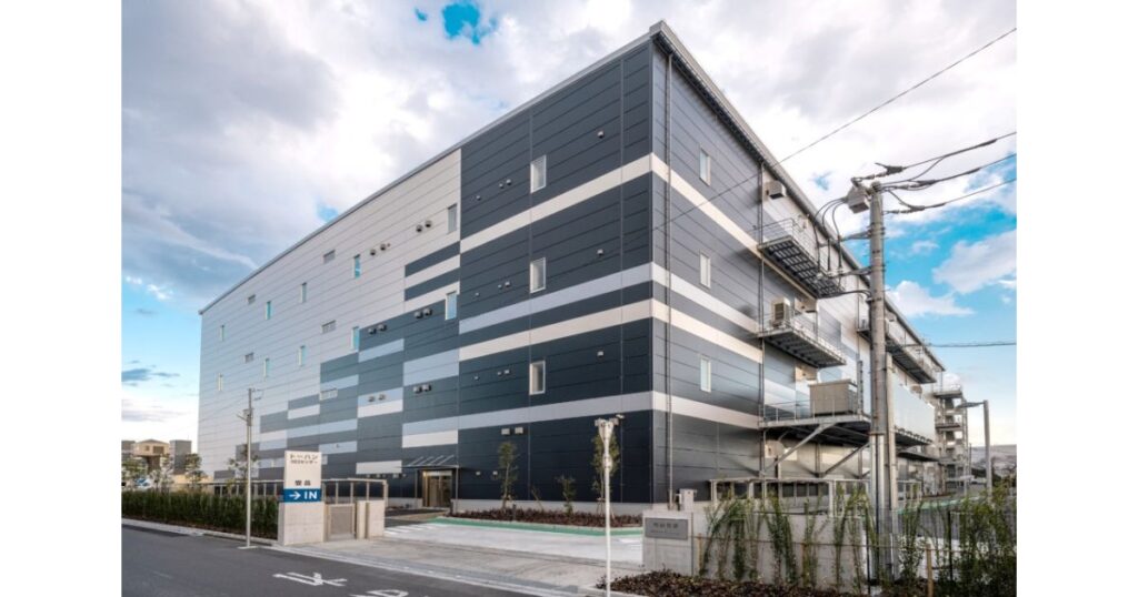 青空の下に建つ、出版取次大手トーハンの巨大な物流センター・倉庫の外観写真