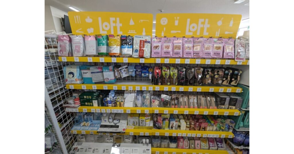 コンビニエンスストア店内に設置された「Loft(ロフト)」の黄色い特設陳列棚。フェイスマスクや化粧品、スキンケア用品などが多数並んでいる様子。