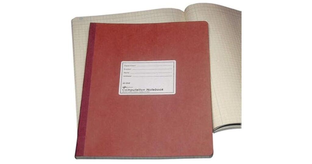 開かれた方眼罫のノートの上に重ねて置かれた、えんじ色の表紙の「Computation Notebook(計算ノート)」。
