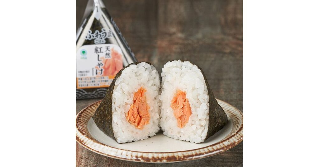 半分に割られた具材たっぷりの天然紅しゃけおにぎりと、ファミリーマート「ごちむすび」のパッケージ