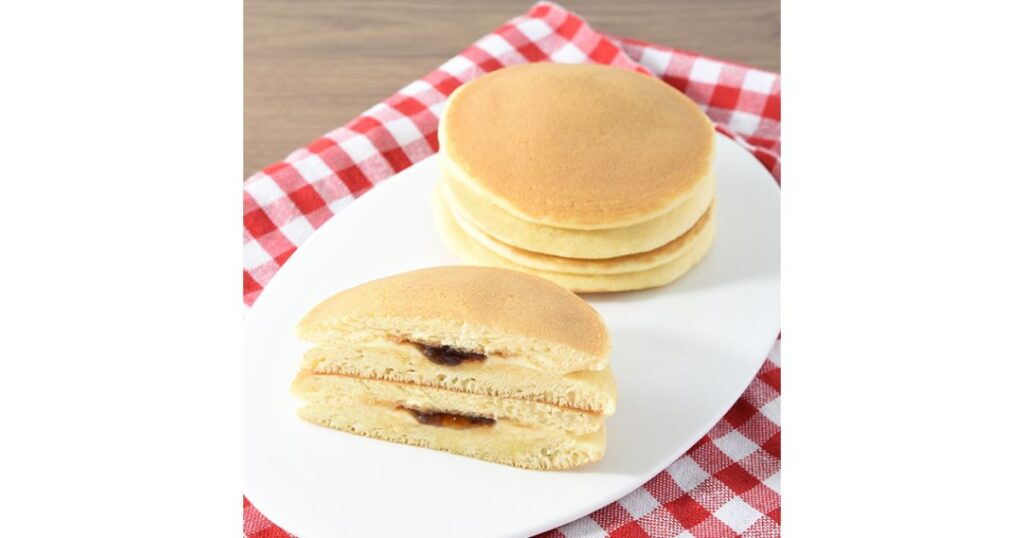 お皿に重ねられたパンケーキと、半分にカットされたメープルシロップ入りパンケーキの断面写真