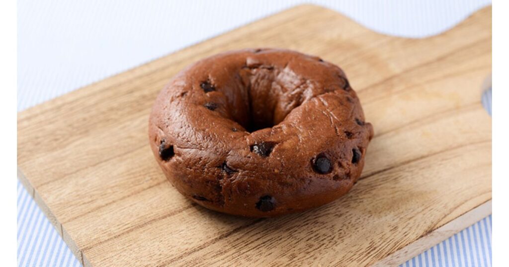 木のカッティングボードの上に置かれた、チョコチップが練り込まれた美味しそうな米粉ベーグル