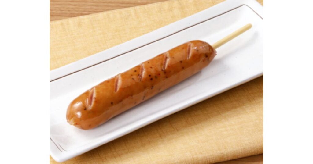 白い長方形のお皿にのった串付きのフランクフルトソーセージ