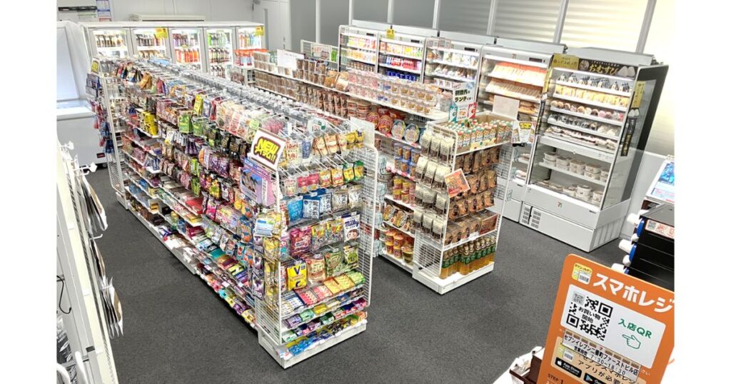 商品が陳列された棚と、すれ違うのが難しそうな狭い通路幅が確認できるコンビニ店内の様子