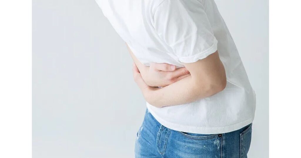 急な腹痛を我慢して下腹部を押さえている男性