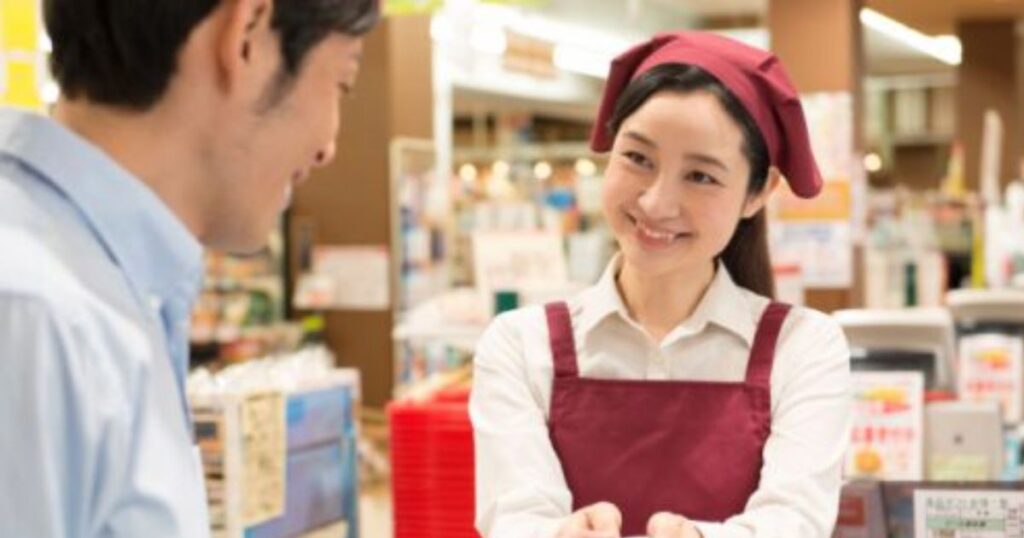 "レジで笑顔で接客をしているコンビニの女性店員