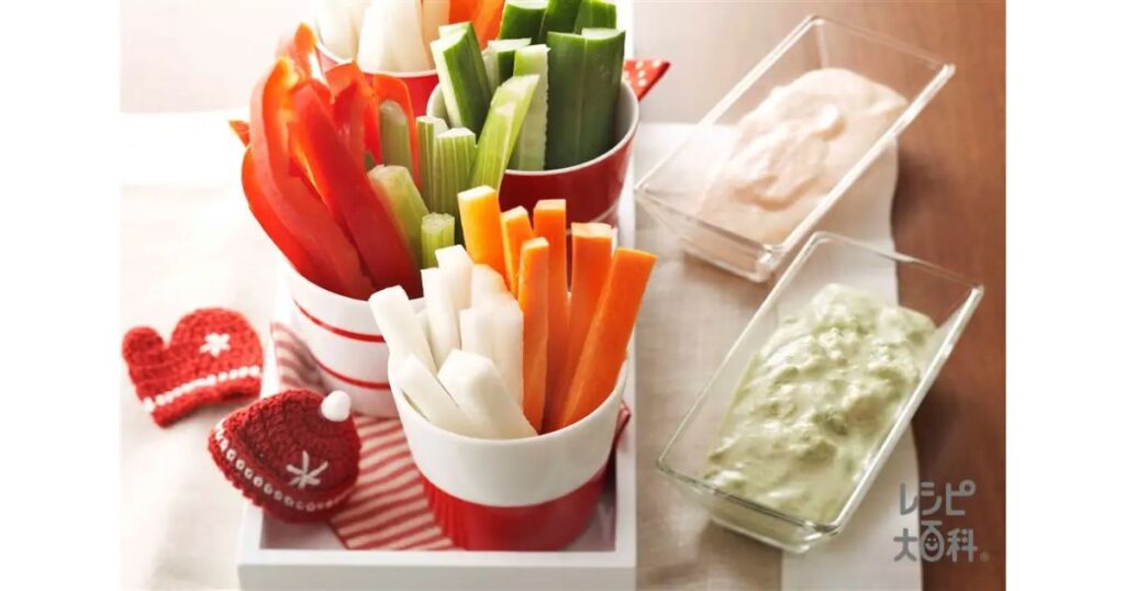 赤と白のカップに盛り付けられた大根、にんじん、きゅうり、パプリカなどの色鮮やかな野菜スティックと2種類のディップソース