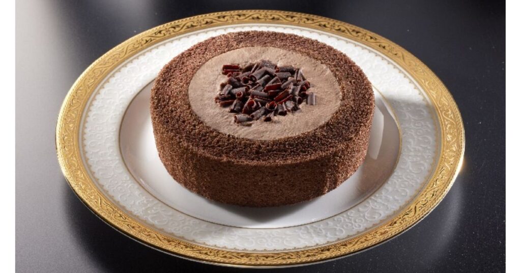 高級感のあるお皿に乗せられた、削りチョコがトッピングされた丸いチョコロールケーキ