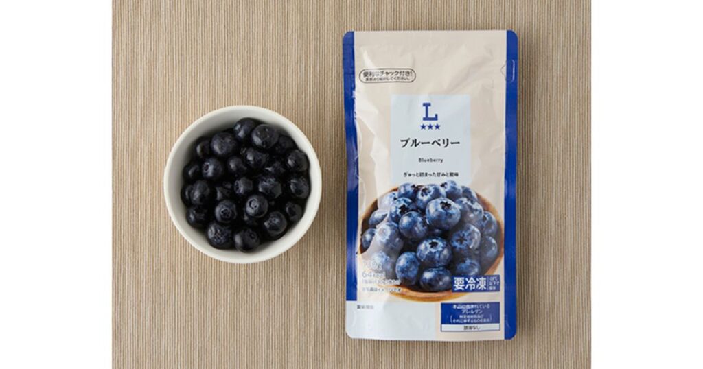 ベージュのランチョンマットの上に、冷凍ブルーベリーが入った白いボウルと、Lawson（ローソン）の「ブルーベリー」冷凍パッケージが並んでいる。