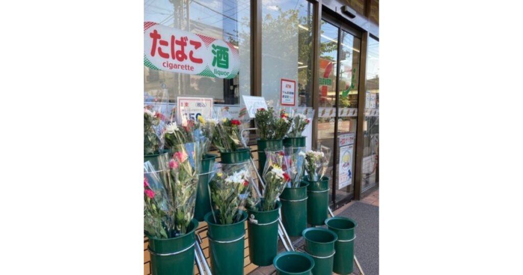 コンビニの店舗入り口付近に設置された、バケツに入れられた仏花や切り花の販売コーナー。