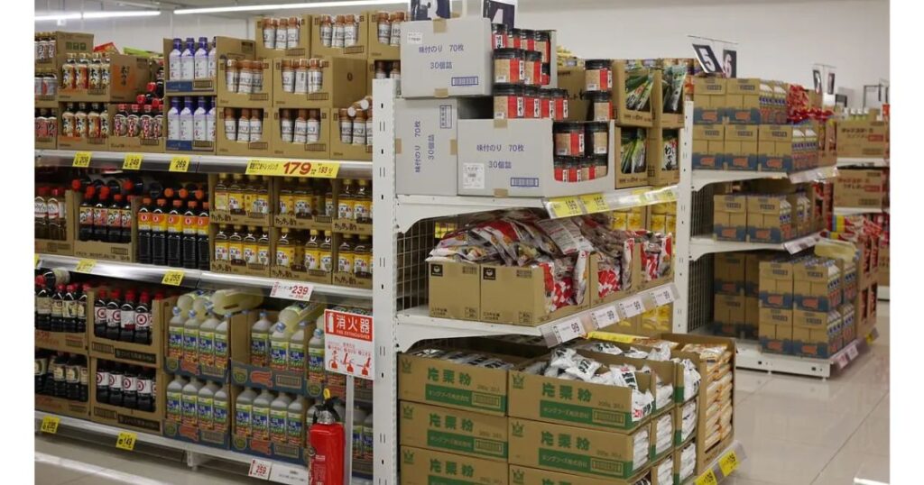 調味料、ドレッシング、加工食品などが隙間なく陳列された小売店の棚の様子。コンビニの「近さ」という優位性を脅かす存在となっている、食品取り扱いを強化したドラッグストアやスーパーの競合環境を象徴している。