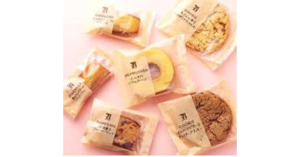 セブンプレミアムの個包装焼き菓子(バウムクーヘン、マドレーヌ、フィナンシェ、クッキー)がピンクの背景に並んでいる様子。