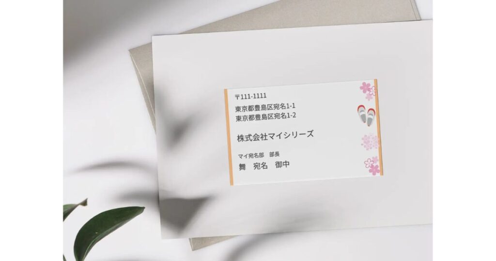 洋形封筒の表面に、花や草履のイラストが添えられた宛名ラベルが綺麗に貼り付けられている写真。
