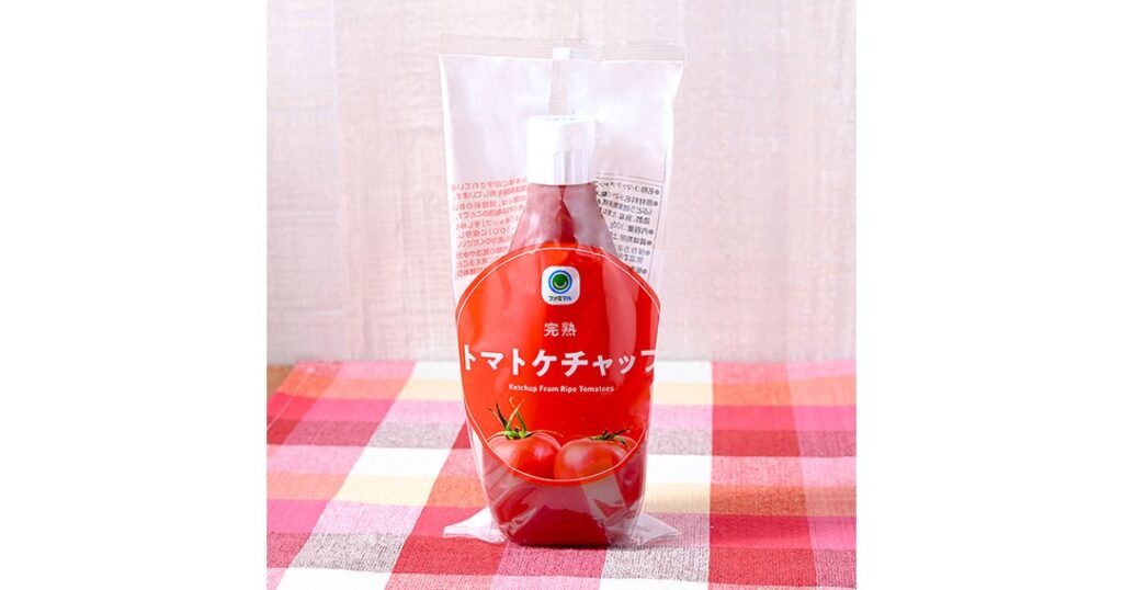 ファミマル「完熟トマトケチャップ」のパッケージ。赤と白のチェック柄のテーブルクロスの上に置かれている。