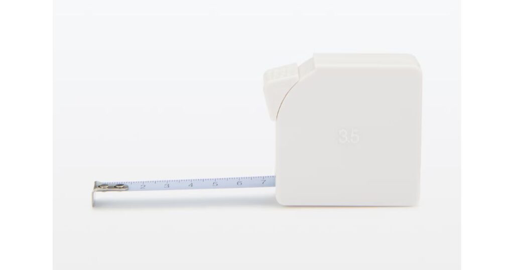白い四角いケースの金属製メジャー（コンベックス）。テープが少し引き出されている状態