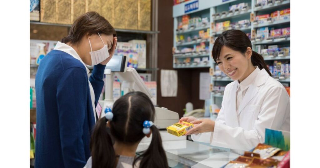 ドラッグストアのレジでスタッフから薬の説明を受ける親子の様子