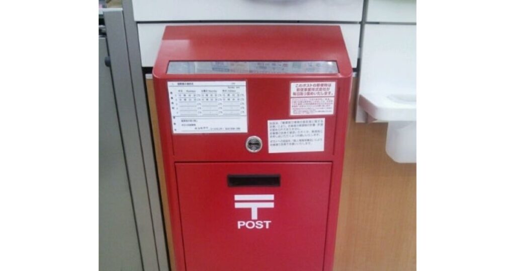 ローソンなどのコンビニ店内に設置されている、赤い薄型の郵便ポストの正面写真。