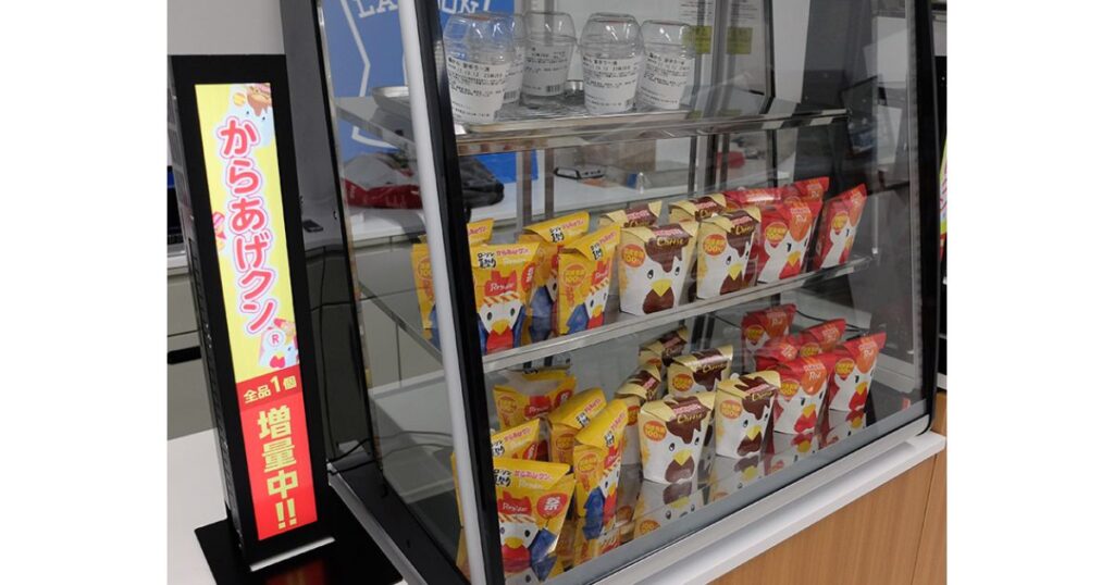 ローソンのレジ横にあるホットスナックケースに陳列された「からあげクン」と、「全品1個増量中!!」と書かれた赤いポップ広告。