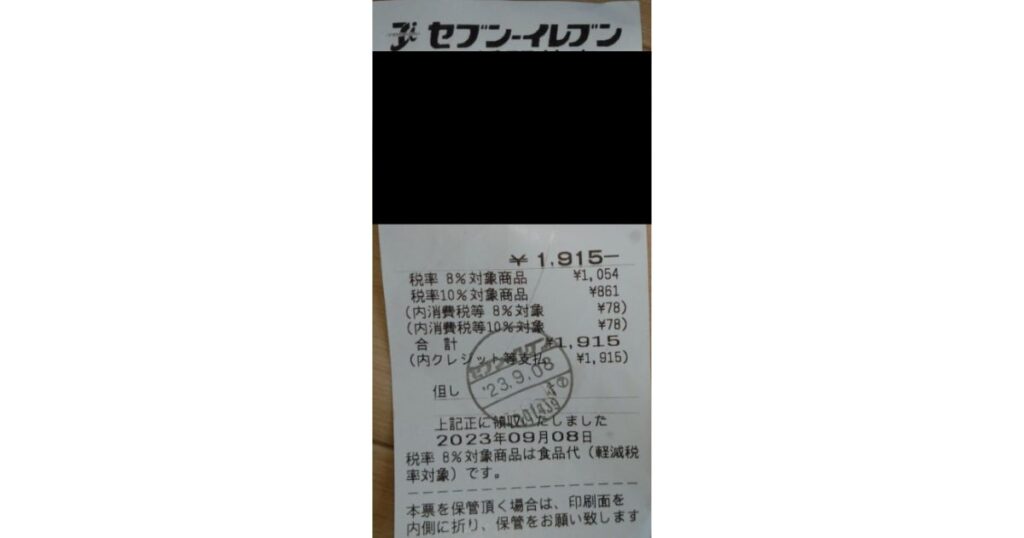 セブン-イレブンのレシートの実物写真。2023年9月8日の取引で、合計金額1,915円。税率8%と10%の内訳や消費税額、軽減税率の対象品目などが印字されている。
