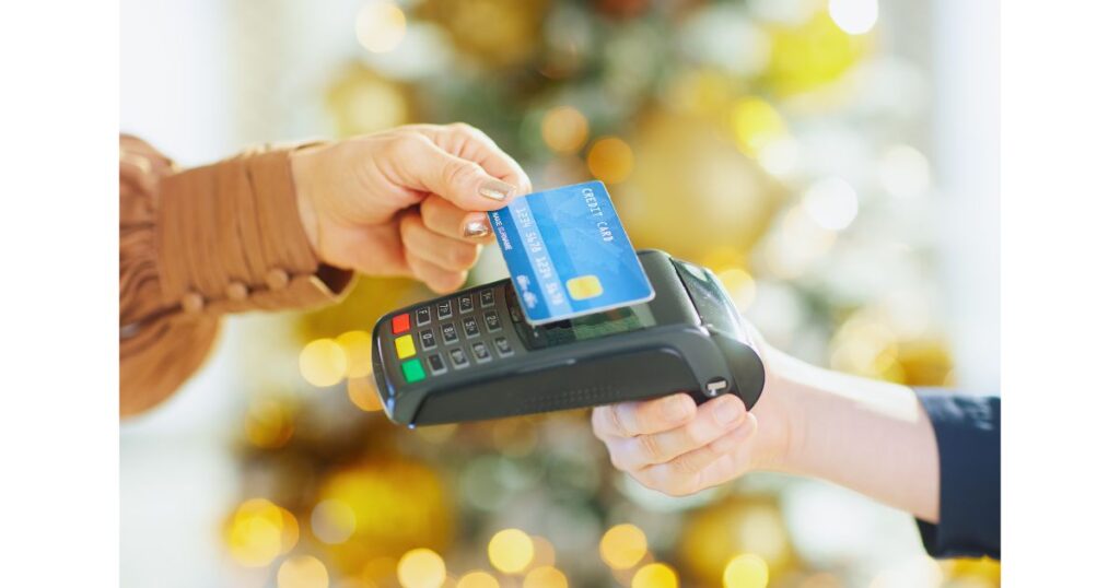 お店の決済端末に青いクレジットカードをかざして、タッチ決済を行っている手元の写真
