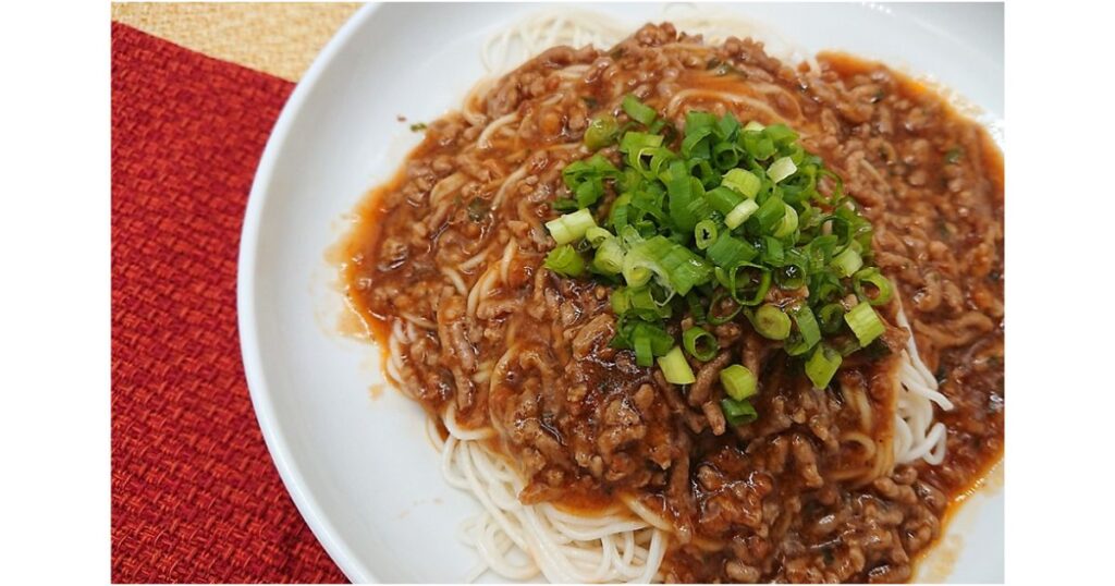 白い豆腐そうめんの上に、たっぷりのひき肉あん（肉味噌）と刻み青ネギがトッピングされたアレンジ料理のアップ写真。