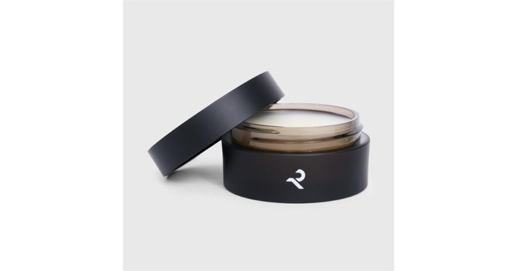 白いロゴが入った黒いシンプルな容器のヘアワックス（またはバーム）。蓋が少し開いて中身が見えている状態