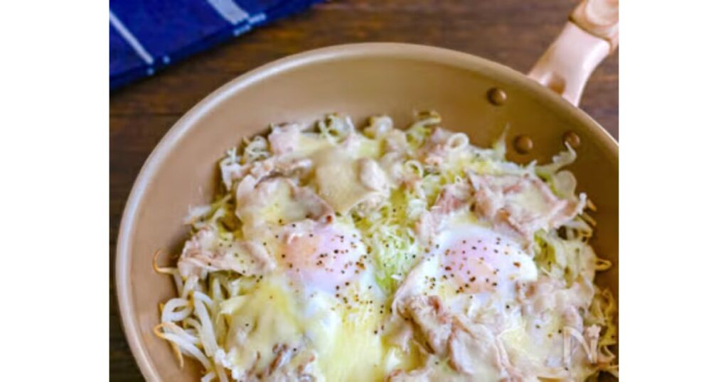 フライパンの中でキャベツともやし、豚肉、卵、とろけるチーズを一緒に蒸し焼きにした温野菜肉皿料理