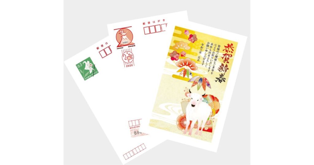 通信面に新年の挨拶と牛のイラストが描かれた年賀はがきと、郵便マークのある宛名面のサンプル。