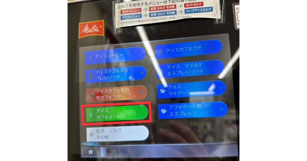 コンビニのデジタル液晶付きコーヒーマシンの画面で、「アイス カフェインレス」のボタンが赤枠で強調されている様子。