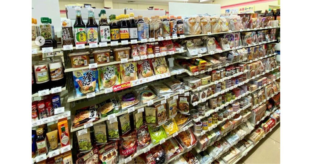 コンビニの調味料コーナーに並ぶ、醤油やポン酢、レトルト食品などの商品棚。