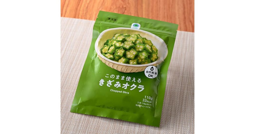 木目調の背景に置かれた、ファミマルの冷凍食品「このまま使えるきざみオクラ」の緑色のパッケージ