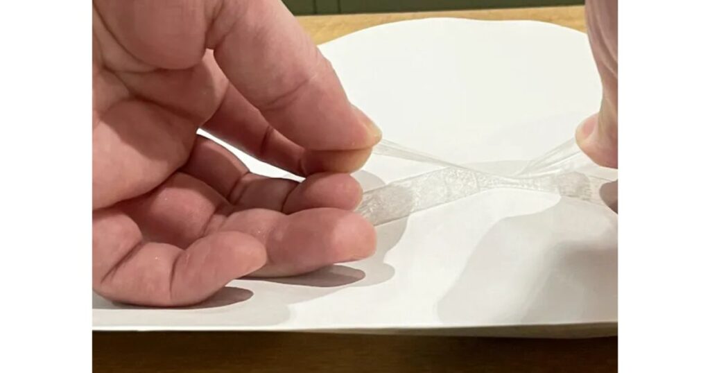 手作業で2枚の用紙の境界線を裏面からだけ強粘着のテープを貼っている
